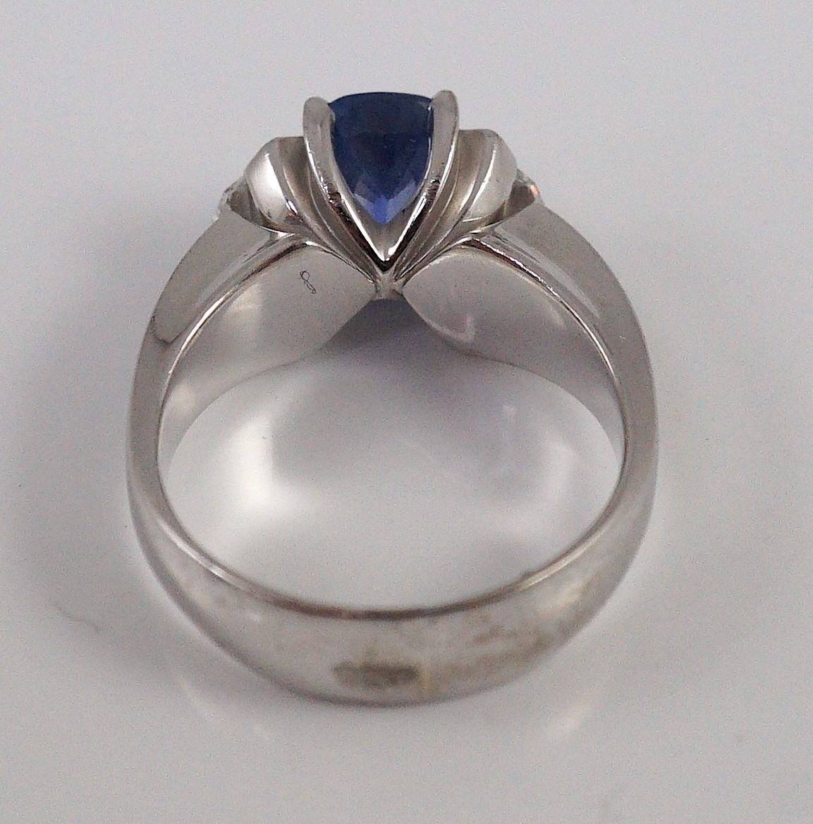 A modern white gold (tests as 18ct), single stone oval cut Ceylon sapphire and two stone shield cut diamond set dress ring, by Musson